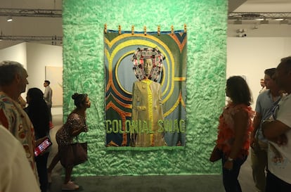 Personas miran el arte textil de April Bey, originaria de Bahamas, titulado 'They Still Glorify Labor and Toxic Resilience but Can't Even Duplicate Their Limbs' (2023), en Miami.