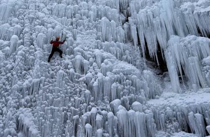 Un hombre sube una pared artificial de hielo en la ciudad checa de Liberec.