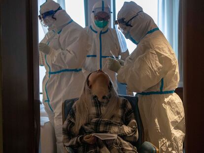 Médicos hacen la prueba del coronavirus a una paciente en un hotel de Wuhan