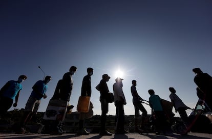 Refugiados del campo de Moria hacen fila antes de ingresar en otra instalación.