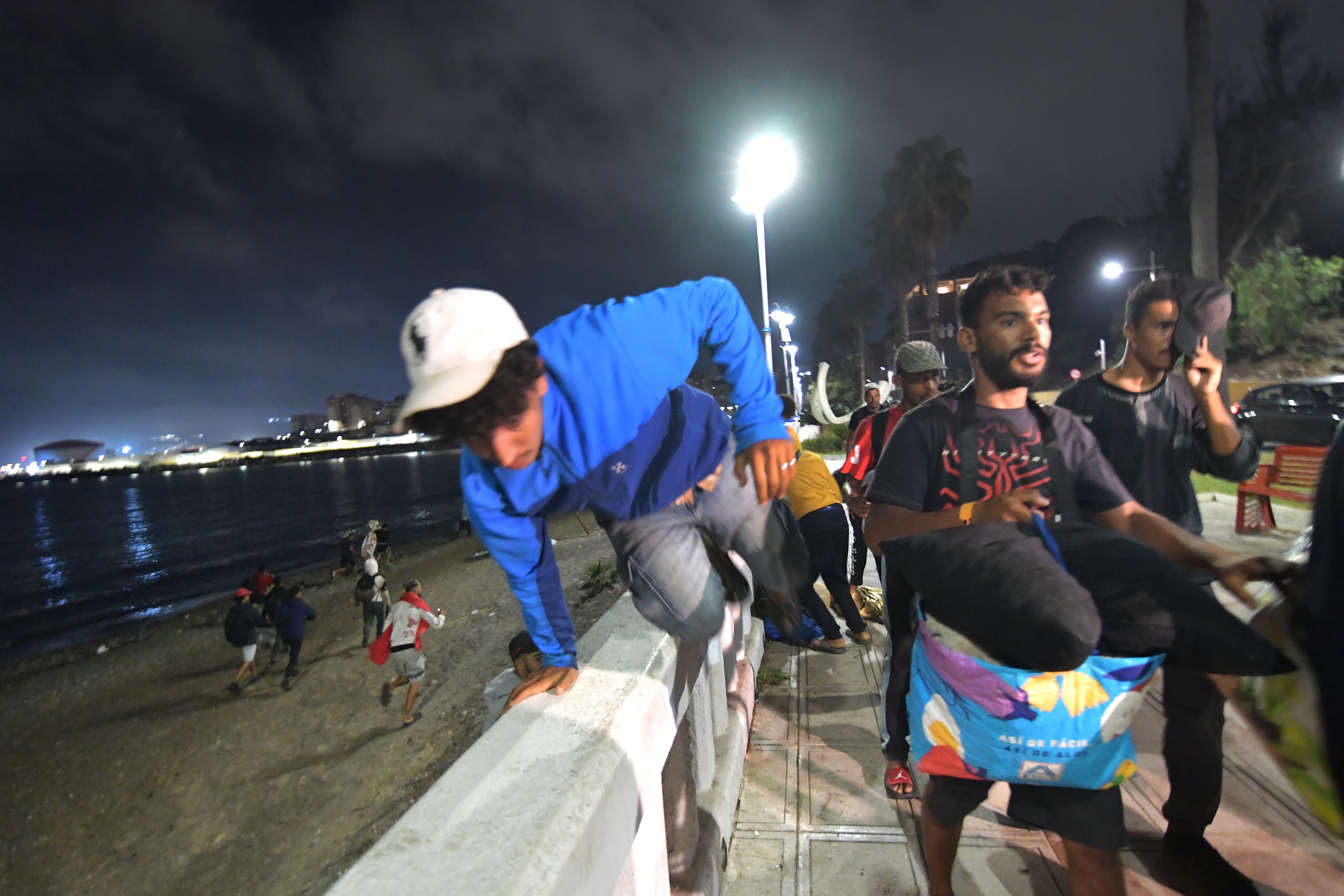 Inmigrantes salían de la playa a la carrera de camino al campamento del puerto, este viernes en Ceuta. 