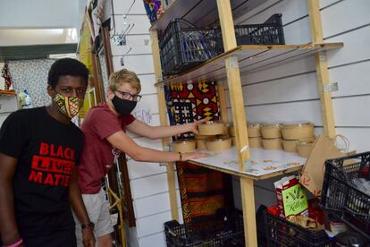 Manuel Bombaerts Keya, de 14 años, (delante) y Guillermo Doz Cosimano, voluntarioas del proyecto, preparan los paquetes de comida que luego Moussa Diop distribuye en la puerta de la Tienda de Besha.