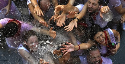 JÓvenes reciben con alivio agua desde los balcones el dÍa del Chupinazo, que da inicio a las famosas fiestas de San FermÍn.
