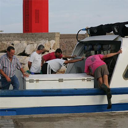 Varios pescadores observan el interior del barco una vez amarrado en Benicarló.
