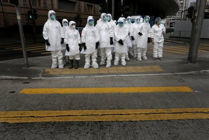 Trabajadores de sanidad antes de entrar a un mercado de aves de corral de venta al por mayor en Hong Kong.