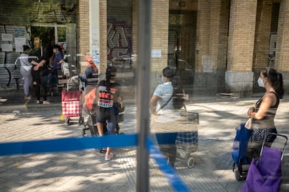 Un grupo de personas hace cola en el banco de alimentos Gran Avenida 24, en el barrio de Orcasitas, Madrid.