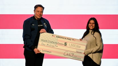 Elon Musk entrega un cheque de un millón de dólares a una de las asistentes a su mitin de Green Bay (Wisconsin) de este domingo.