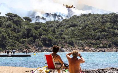 Dos mujeres observan un avión de extinción de incendios sobre un fuego en La Croix-Valmer, cerca de Saint-Tropez, en el sur de Francia.