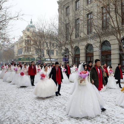 Las parejas recién casadas chinas desfilan en el centro de la calle durante una ceremonia de boda colectiva en el 34º festival internacional de esculturas de hielo y nieve de Harbin, en Harbin (China).