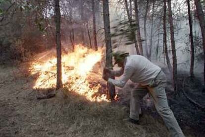 Un vecino participa en la extinción del fuego en la población barcelonesa de Serrateix.