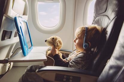 Little boy watching something on a digital tablet with his plush dog while flying on an airplane