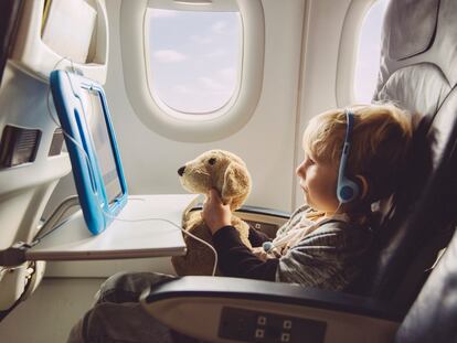 Little boy watching something on a digital tablet with his plush dog while flying on an airplane