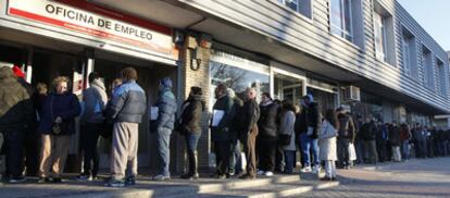 A line of unemployed people waits outside a Madrid employment office.