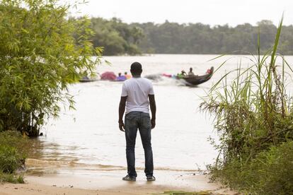 Un surinamés mira hacia una canoa que cruza el rio Maroni frente a Saint Laurent du Maroni.