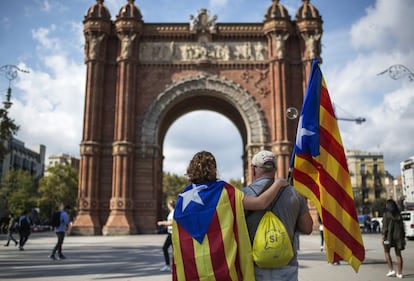 Dos manifestantes, favorables a la independencia de Cataluña, portan banderas independentistas camino de la concentración, junto al Arco del Triunfo, en Barcelona.