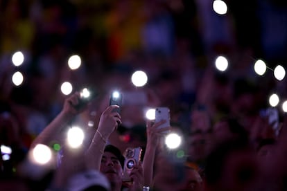 Aficionados en la tribuna encienden las luces de sus teléfonos mientras el juego se retrasa debido a incidentes fuera del estadio antes del partido.