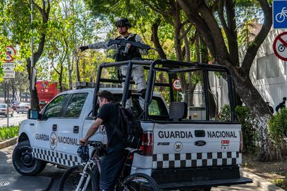 Un integrante de la Guardia Nacional indica a un ciclista que rodee la camioneta de la agencia, que bloquea el paso frente a la Fiscalía General de la República.