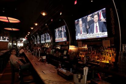 Un hombre mira la televisión de un bar que retransmite la declaración de James Comey, exdirector del FBI, en Nueva York.