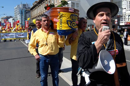 Unos 200 carteros se concentraron ayer ante la sede de Correos en A Coruña y pasearon un féretro para escenificar la "muerte" del servicio público.