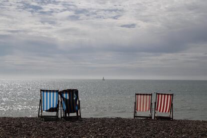 Una mujer toma el sol en una tumbona junto al mar en un día soleado en la playa de Brighton, Reino Unido.
