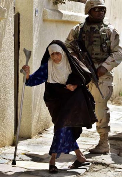 Una mujer camina delante de un soldado de EE UU en Bagdad.