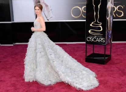 Amy Adams escoge un vestido gris perla de Oscar de la Renta con escote palabra de honor y falda suflé con varias capas de gasa. Y el pelo recogido. Un modelo que produce una extraña sensación de déjà vu y recuerda poderosamente al que lució Penélope Cruz en 2007.