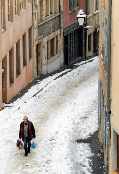 Un hombre camina por una callle nevada de Lyon.