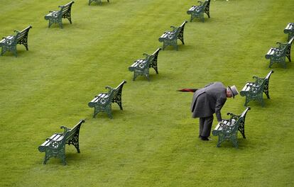 Un aficionado limpia un banco en el Hipódromo de Ascot antes de iniciarse las carreras.