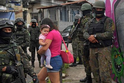 Mulher carrega bebê na comunidade Vila Kennedy, no Rio.