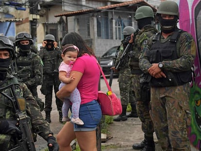 Mulher carrega bebê na comunidade Vila Kennedy, no Rio.