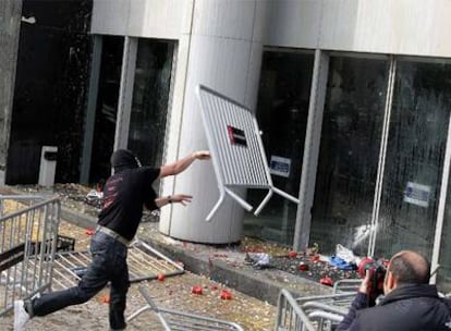Un manifestante contra los despidos de Nissan tira una valla contra la sede en Barcelona.