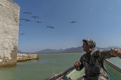 Josué Vázquez, el presidente de la Cooperativa de Pescadores de la presa Benito Juárez, rema una lancha cerca del templo.