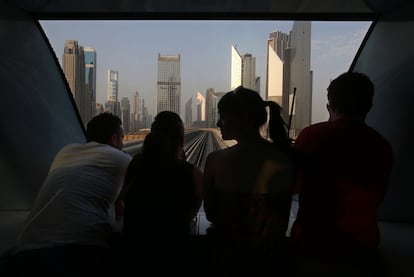 Pasajeros del metro de Dubai (Emiratos Árabes Unidos) observan el perfil de la ciudad al volver del trabajo.