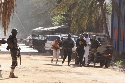 Varios hombres armados mantienen secuestradas a unas 170 personas en el interior del hotel Radisson de Bamako, la capital de Malí, En la imagen, un grupo de personas en el exterior del hotel.