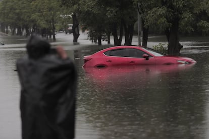 Un hombre toma la foto de un coche parcialmente sumergido en una calle inundada, este viernes en Lázaro Cárdenas, Michoacán.