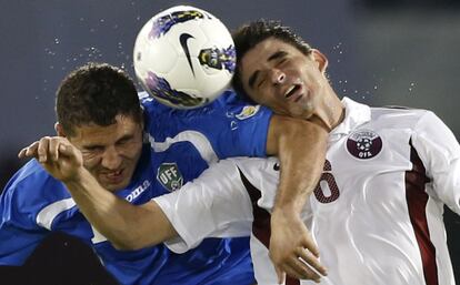 El jugador de Qatar Marcone Amaral pelea el balón con Ulugbek Bakaev de Uzbekistán