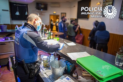 Un agente levanta el atestado de la intervención en el local del distrito de Puente de Vallecas de la capital, la madrugada del viernes al sábado.