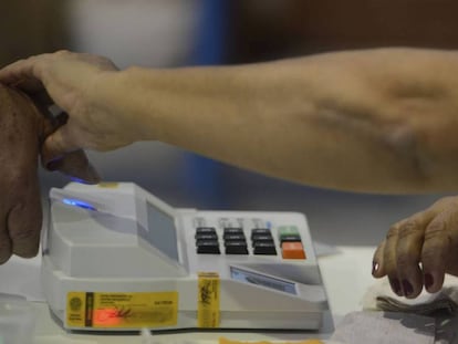 Mesária colhe digital de eleitor na eleição municipal de 2016 em Niterói.