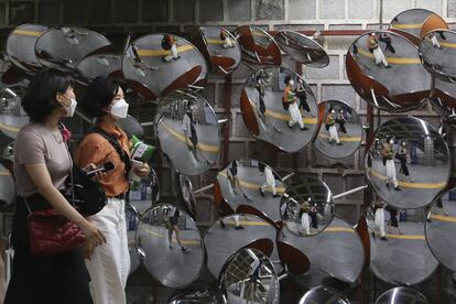 Varias personas con mascarillas se reflejan en los espejos de una estación de Corea del Sur.