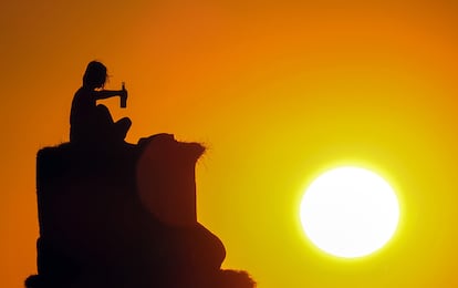 Un hombre mira el atardecer sentado sobre balas de paja con una botella en la mano, en Tempelhof (Berlín).