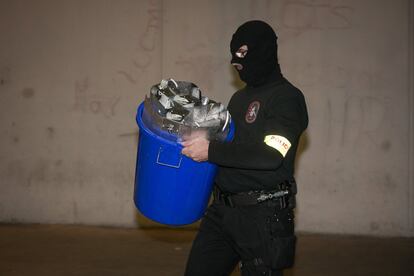 Un agent transporta material elèctric que es feia servir per al cultiu de marihuana decomissat en un dels escorcolls que s'han fet aquesta matinada a la Mina, a Sant Adrià de Besòs.