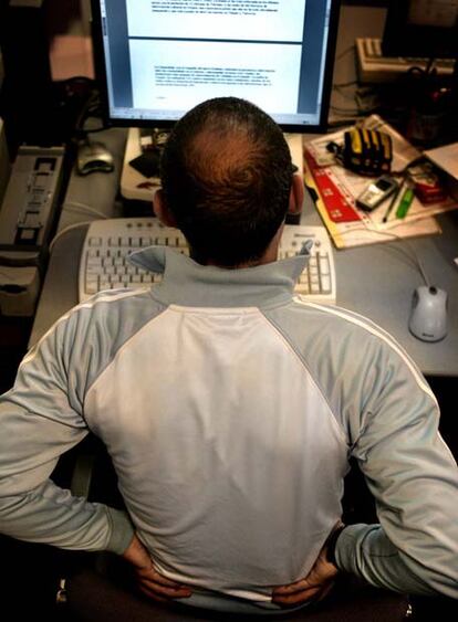 Un trabajador con dolores de espalda ante un ordenador.