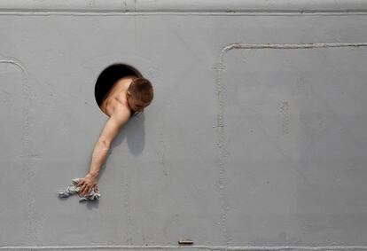 Un marine ruso limpia el buque Admiral Vinogradov desde un ojo de buey durante una visita al puerto de Manila, Filipinas. 