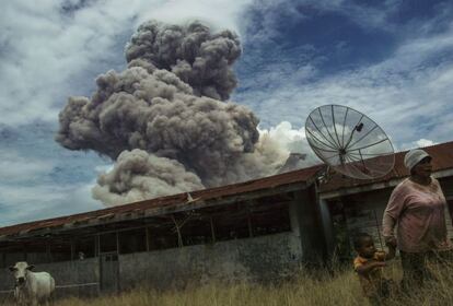 en la imagen una mujer y su hijo abandonan el edificio del colegio ante la necesidad de abandonar la zona por la eclosión del volcán. Muchos de las personas que abandonaron sus residencias tras las actividades de 2014 tendrán que volver a salir de sus casas.