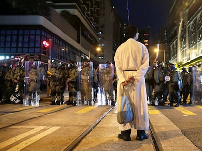 Un sacerdote frente a una fila de policías antidisturbios durante una protesta en Hong Kong este domingo.