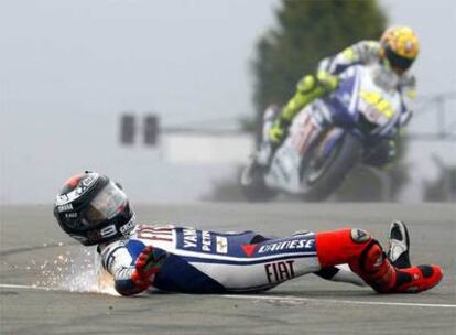 Jorge Lorenzo rueda por el suelo tras su caída. Al fondo, Valentino Rossi.