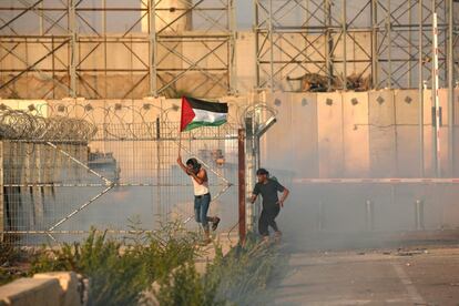 Un palestino que sostiene una bandera nacional trata de huir del gas lacrimógeno disparado por las fuerzas israelíes durante una protesta en el cruce de Erez con Israel, en el norte de la Franja de Gaza.