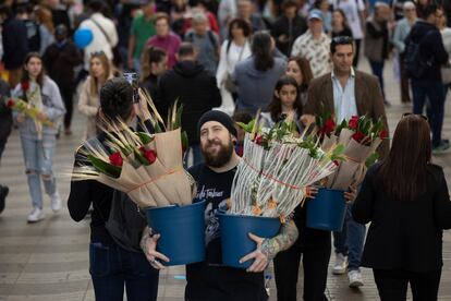 Un hombre carga con dos cubos de rosas en el inicio de la Rambla.