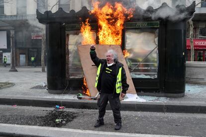 Un manifestante de los 'chalecos amarillos' gesticula frente a un quiosco en llamas durante los enfrentamientos con las fuerzas de la policía antidisturbios en los Campos Elíseos en París, el 16 de marzo de 2019.