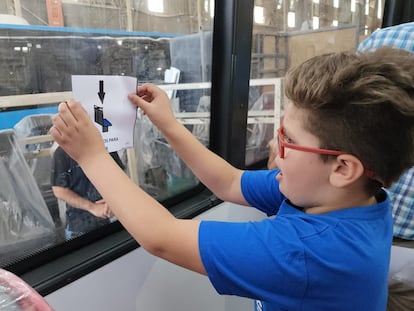 Un niño coloca señalización pictográfica en uno de los autobuses de la Línea 85 bonaerense.